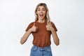 Excited smiling woman showing thumbs up, positive reaction to something great, standing amazed against white background