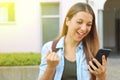 Excited student girl reading amazing news on line in a smart phone on the street. Copy space Royalty Free Stock Photo