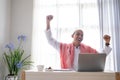 success businessman raise his arm while using laptop