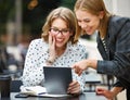 Excited successful business women at outdoor cafe looking at digital tablet with happy face expression Royalty Free Stock Photo