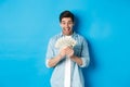 Excited successful man counting money, looking satisfied at cash and smiling, standing over blue background Royalty Free Stock Photo