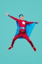 Excited superhero boy jumping in studio