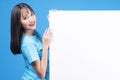 Excited surprise Asian woman presenting on white placard empty copy space standing over isolated blue background. Teenager asia