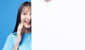 Excited surprise Asian woman using white placard empty copy space cover eye standing over isolated blue background. Teenager asia