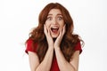 Excited and surprised redhead woman scream from amazement, looking fascinated and impressed, checking out awesome promo