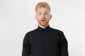 Excited surprised shock young shouting man isolated on gray background. Happy Redhead guy with red beard in black stylish shirt.