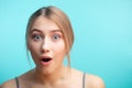 Excited surprised woman dressed in shirt over blue background.