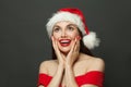 Excited surprised woman in Santa hat smiling on black. Christmas holiday and New Year party portrait Royalty Free Stock Photo