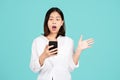 Excited and surprised young woman looks at the smartphone in her hand. She screams with happiness isolated on a bright green Royalty Free Stock Photo