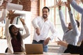 Excited team celebrating successful project accomplishment throwing papers up