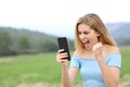 Excited teen checking content on smart phone in a field