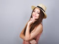 Excited tinking happy woman in pink t-shirt and suumer straw hat on blue background