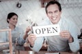 Excited waiter smiling and holding the open sign