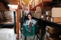 Excited warehouse workers playing with a cart, man pushes woman riding in it Royalty Free Stock Photo