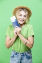 Excited Winsome Lovely Smiling Young Girl in Straw Hat Holding Passport with Tickets isolated Over Trendy Green