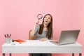 Excited woman in casual clothes looking up through magnifying glass work at white desk with contemporary pc laptop Royalty Free Stock Photo