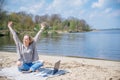 Excited woman, female freelancer with laptop keeping arms raised while working remotely during summer vacation.