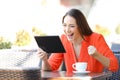 Excited woman finding online offers on tablet in a bar