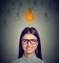 Excited woman in glasses looking up at bright light bulb above head has an idea Royalty Free Stock Photo