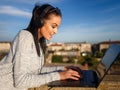 Excited woman listening music and typing on laptop outdoor Royalty Free Stock Photo