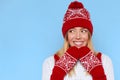 Excited woman looking sideways in excitement. Surprised christmas girl wearing knitted warm hat and mittens, isolated on blue