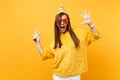 Excited woman in orange funny glasses birthday hat with playing pipe spreading hands, celebrating, enjoying holiday