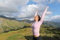 Excited woman raising arms in the mountain celebrating