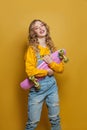 Excited woman with skateboard on bright yellow background. Positive emotion Royalty Free Stock Photo