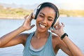 Excited woman smiling and listening to music with water in the background. Happy young female enjoying tunes on her Royalty Free Stock Photo
