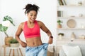 Excited Woman Wearing Too Big Jeans After Weight Loss Indoor