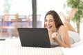 Excited woman winning online watching laptop