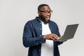 Excited young African American man standing isolated on grey wall holding laptop computer Royalty Free Stock Photo