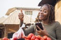 excited young african woman in a local african market using her smartphone giving thumbs up Royalty Free Stock Photo