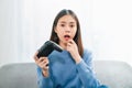 Excited young Asian woman sitting on sofa and holding joystick with playing games in the living room at home. Royalty Free Stock Photo