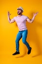 Excited young bearded fitness sporty guy in hat and sunglasses Jump very emotionally isolated on yellow background