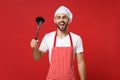 Excited young bearded male chef cook or baker man in striped apron toque chefs hat posing isolated on red wall