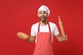 Excited young bearded male chef cook or baker man in striped apron white t-shirt toque chefs hat posing isolated on red Royalty Free Stock Photo