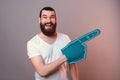 Excited young bearded man wearing blue foam fan glove is pointing aside. Royalty Free Stock Photo