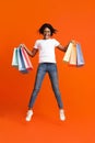 Excited black lady with shopping bags jumping up