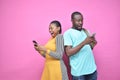 excited young black people standing back to back viewing contents on their phones, looking surprised, young african man and woman