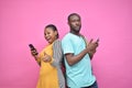 excited young black people standing back to back viewing contents on their phones, looking surprised, young african man and woman