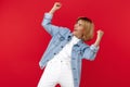 Excited young blonde woman in casual white celebrating success with hands up over red background. Royalty Free Stock Photo