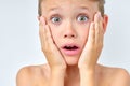 Excited young boy touching cheeks, looking surprised, posing at camera, close-up Royalty Free Stock Photo