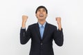 Excited young business Asian man raising his fists with happy delighted face, celebrating success isolated on white background. Royalty Free Stock Photo