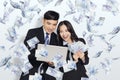 Excited young business man and woman holding laptop with dollars under money rain Royalty Free Stock Photo