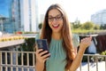 Excited young business woman receiving good news on mobile phone celebrating with fist up in modern city district in spring time Royalty Free Stock Photo