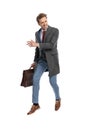 Excited young businessman with suitcase looking to side and leaping up Royalty Free Stock Photo