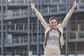 Excited young businesswoman with arms raised standing against office building Royalty Free Stock Photo