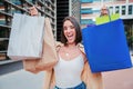 Excited young caucasian lady holding colorful paper shopping bags while showing a smiley expression and having a good Royalty Free Stock Photo