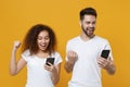 Excited young couple friends european guy african american girl in white t-shirts isolated on yellow background. People Royalty Free Stock Photo